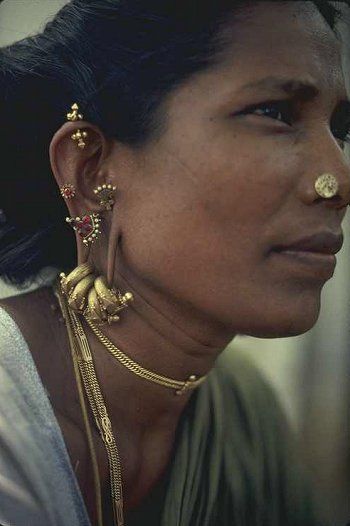 a woman with gold nose rings and piercings on her nose is looking off to the side