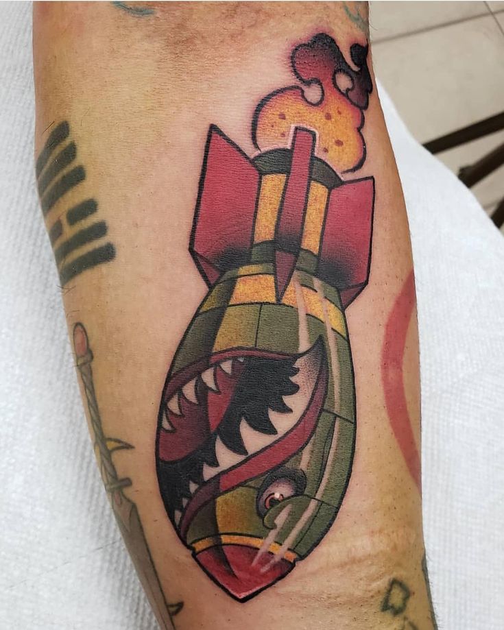 a man with a tattoo on his arm has a colorful heart shaped object in the shape of a bomb