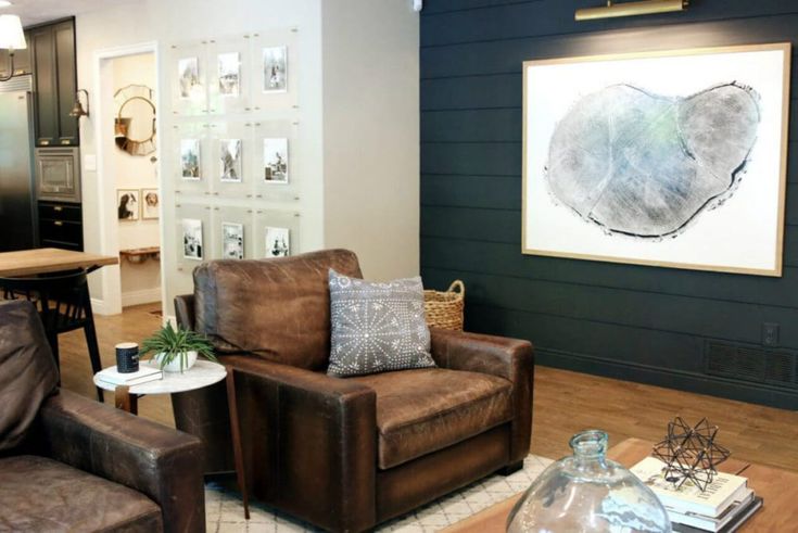 a living room with two brown chairs and a table in front of a painting on the wall