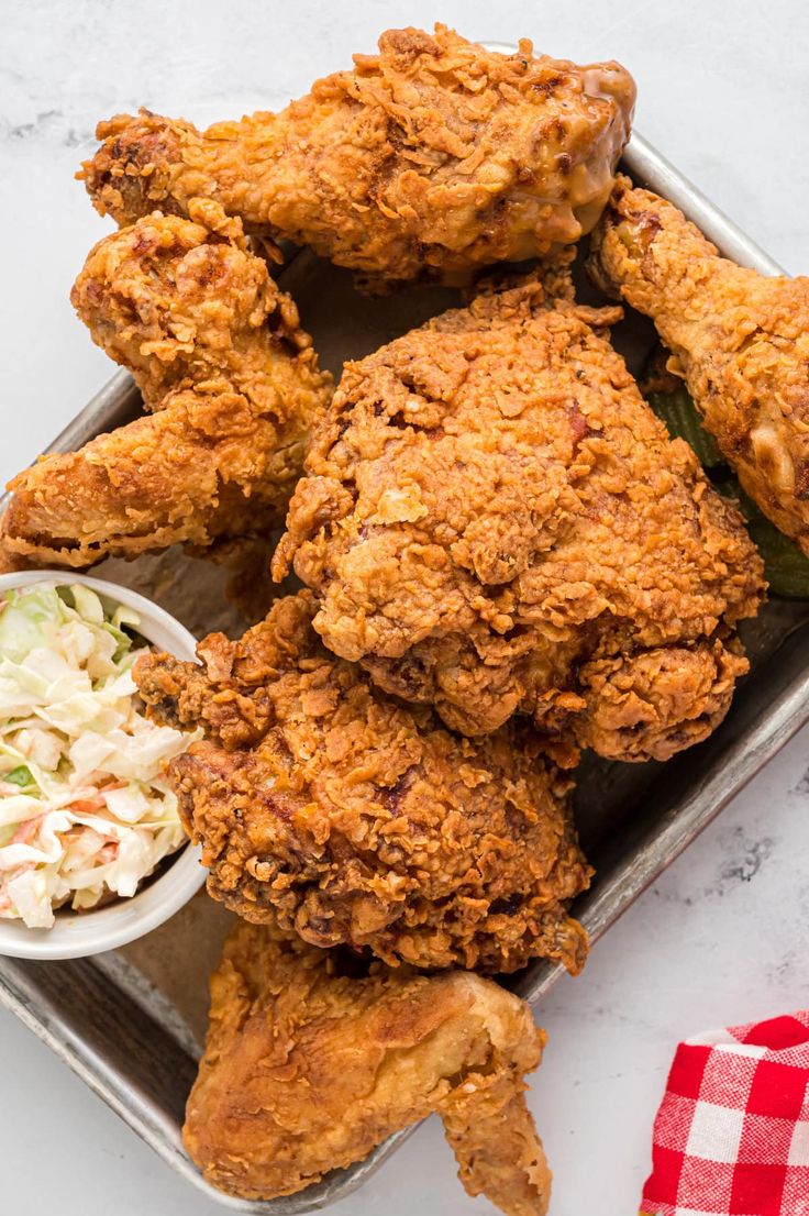 fried chicken and coleslaw are served on a tray