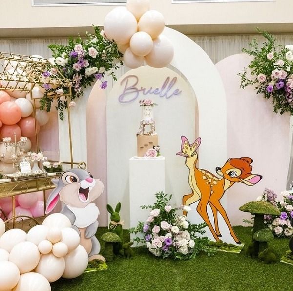 a table topped with balloons and animals next to a cake stand filled with cakes, bunnies and other decorations