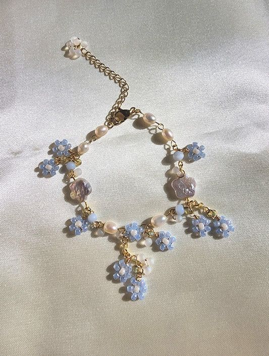 a blue and white bracelet with charms on it's sides is laying on a bed