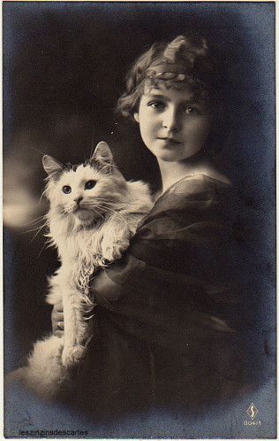 an old black and white photo of a woman holding a cat in her arms with green eyes