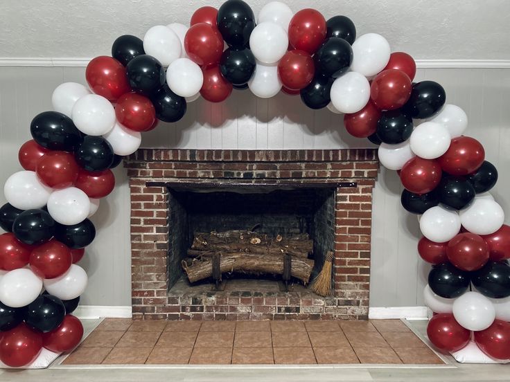 a fireplace decorated with red, white and black balloons