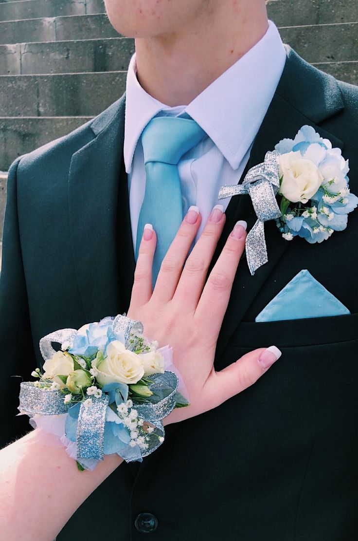 a close up of a person wearing a suit and tie with flowers on his lapel