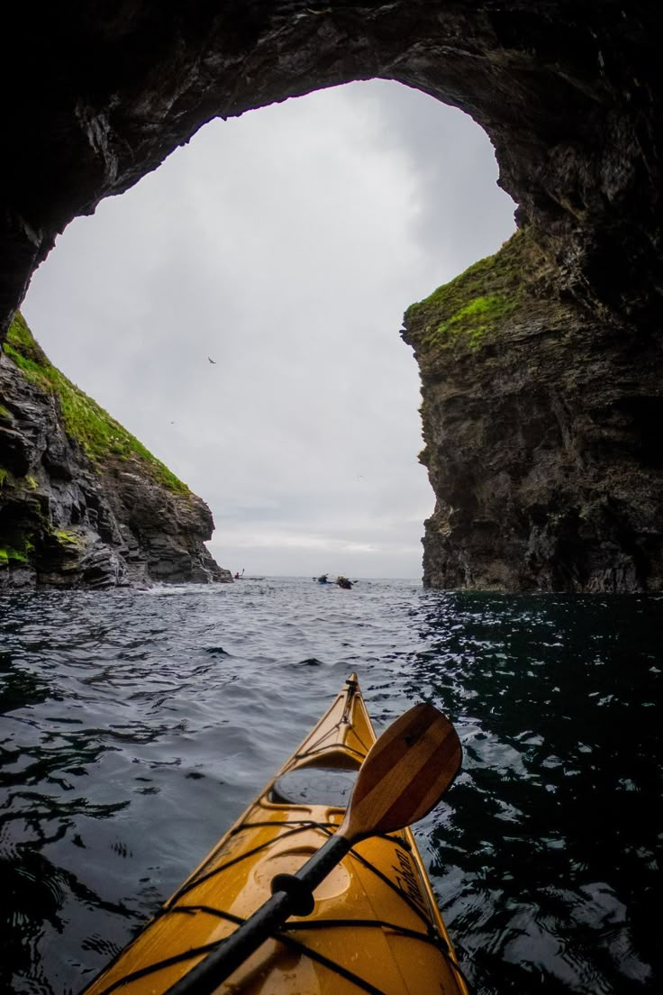 a yellow kayak is in the water near a cave