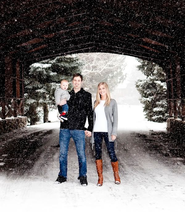 three people are standing in the snow under an overpass with trees on either side