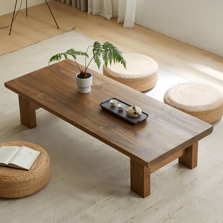 a wooden table sitting on top of a white rug next to a potted plant