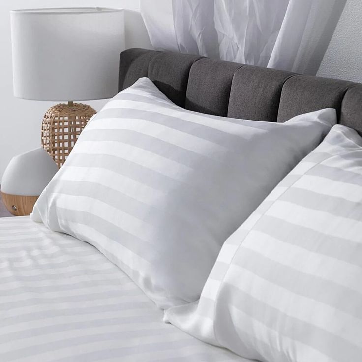 a bed with white and grey striped pillows