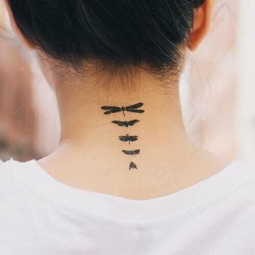 a woman's neck with three dragonflies on her back and the word love written across it