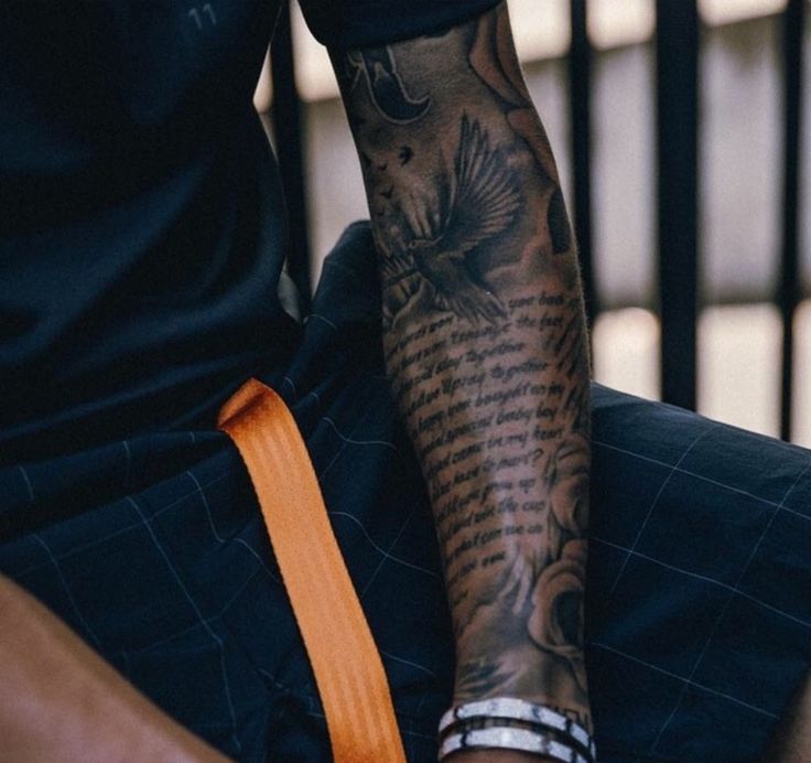 a man with a tattoo on his arm holding onto an orange strap that is attached to his leg