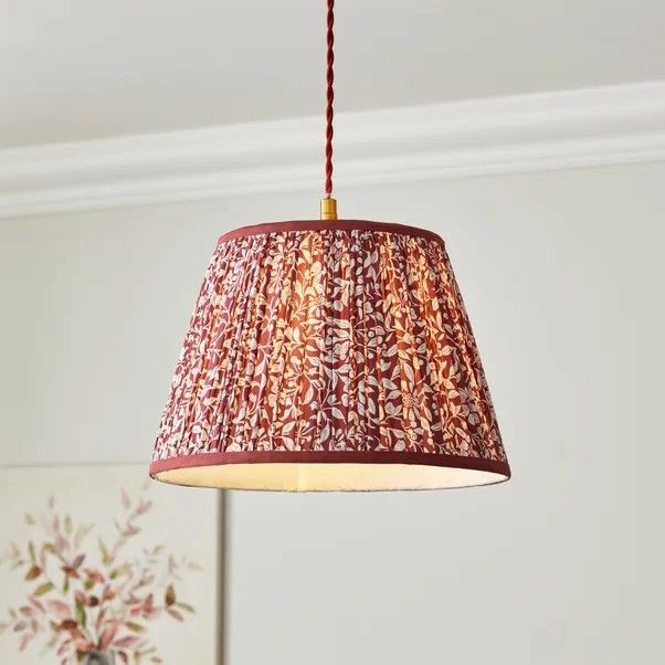 a red lamp hanging from a ceiling in a room with a painting on the wall