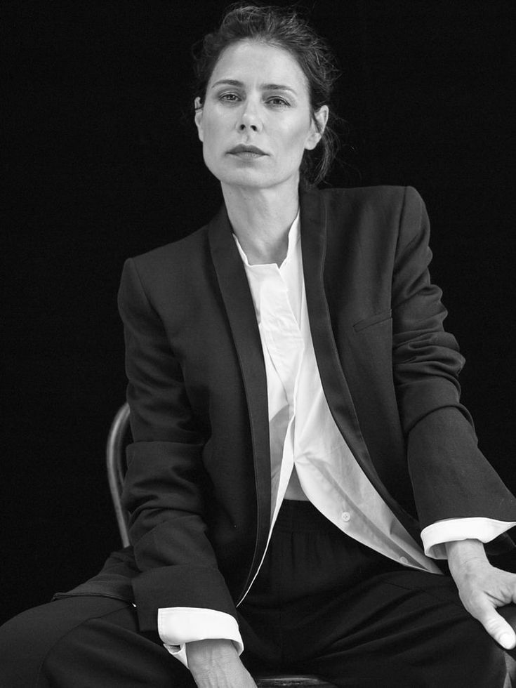 a woman sitting in a chair wearing a suit