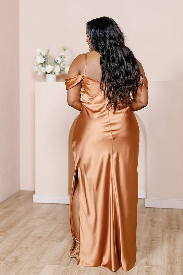 a woman in a gold dress standing on a wooden floor with her back to the camera