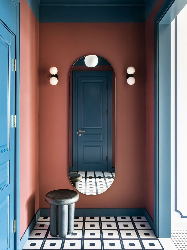 a blue door and mirror in a room with black and white floor tiles on the floor