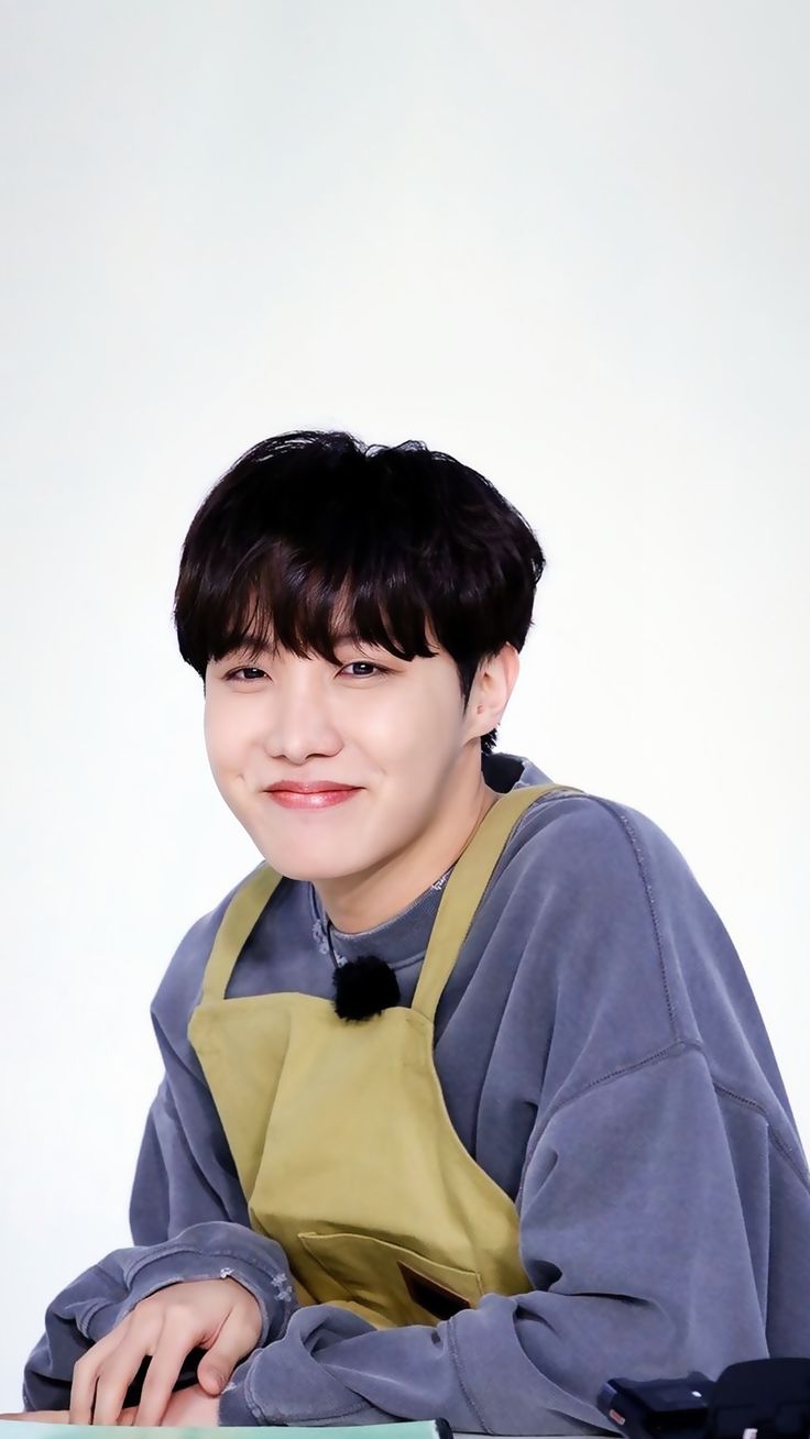 a young man sitting at a table with an apron over his shoulder and smiling for the camera