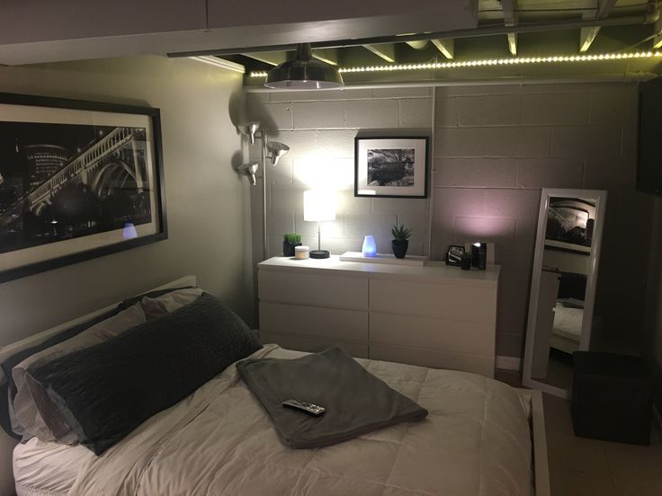 a bedroom with a bed, dresser and pictures on the wall above it in an apartment