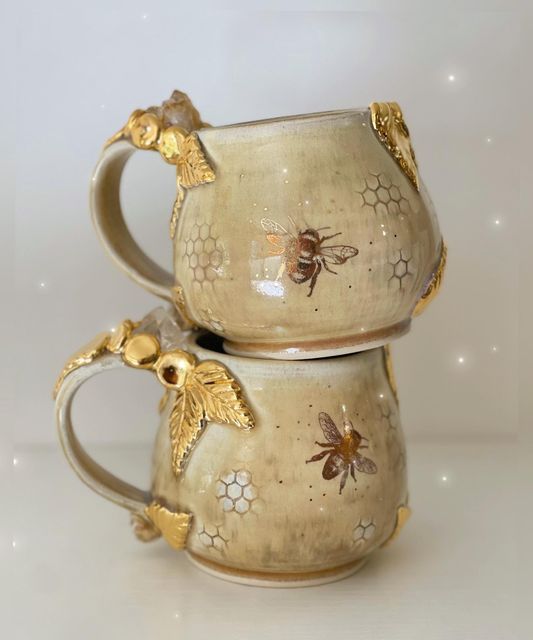 two coffee mugs with bees on them sitting side by side in front of a white background