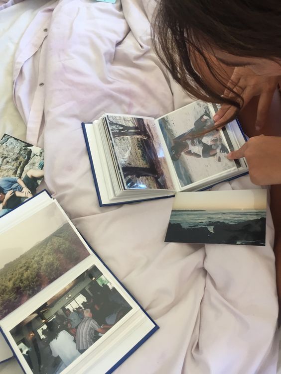 a person laying on a bed with some pictures and books in front of them that are open