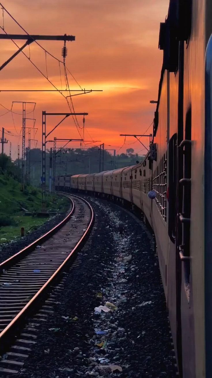 the train is going down the railroad tracks at sunset or dawn, with its lights on