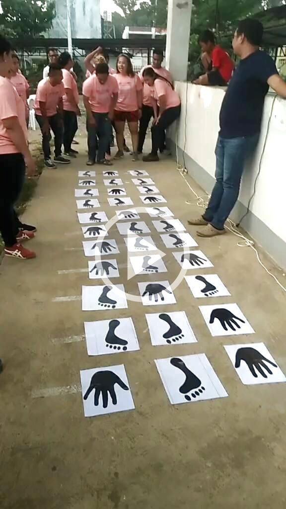 a group of people standing next to each other in front of white handprints on the ground