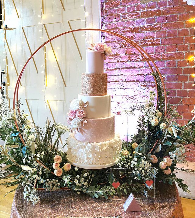 a three tiered wedding cake sitting on top of a table with flowers and greenery