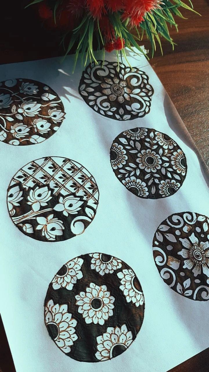 four black and white plates on a table next to a vase with red flowers in it