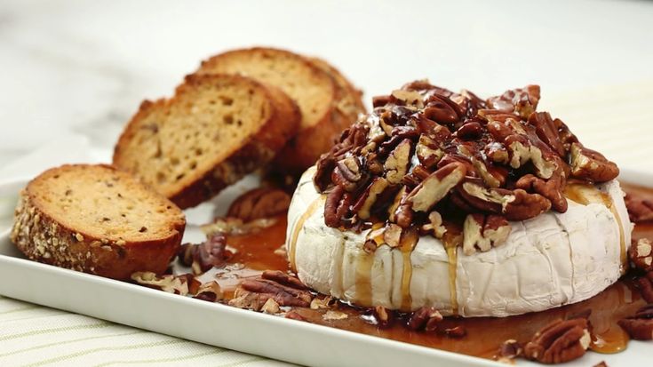 a white plate topped with bananas and pecans covered in caramel sauce next to slices of bread