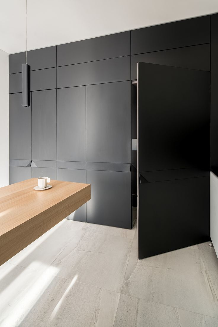 a wooden table sitting in front of a black wall next to a white counter top