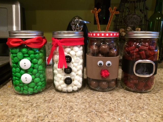 four jars filled with candy and candies decorated to look like reindeers, snowmen, and rudolph's nose