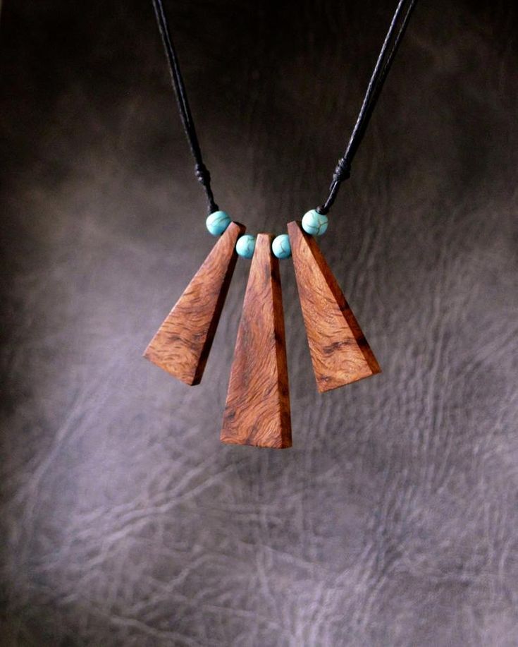 a wooden necklace with turquoise beads hanging from it's end on a black cord