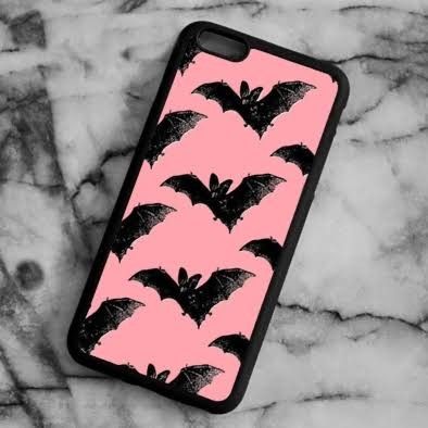 a pink and black phone case with bat designs on it sitting on a marble surface