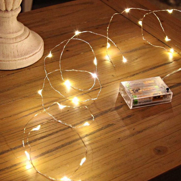 a string of fairy lights sitting on top of a wooden table next to a remote control