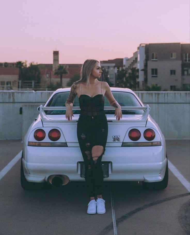 a woman sitting on the back of a white car