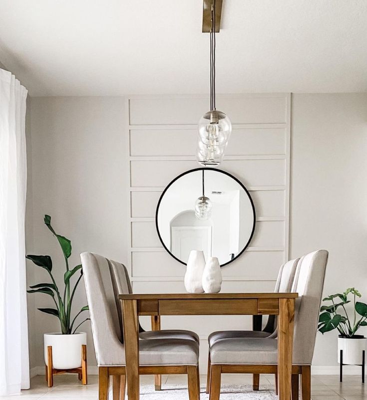 a dining room table with chairs and a round mirror