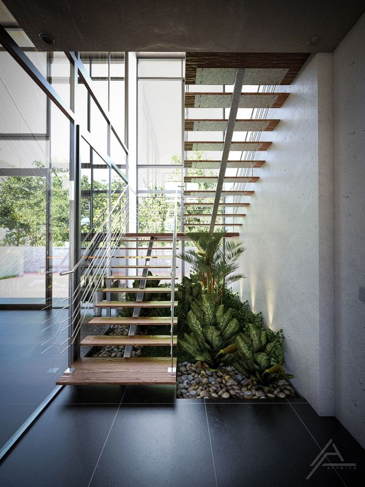 an indoor stair case with plants and rocks on the bottom, in front of a glass wall