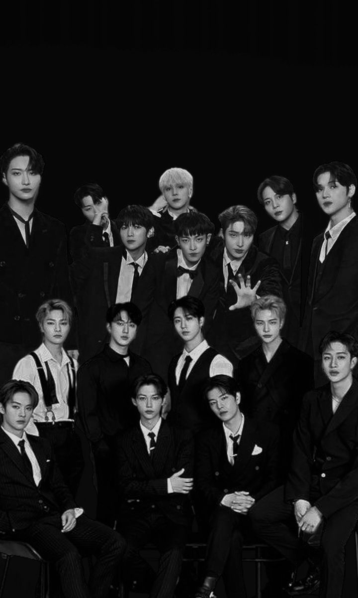 black and white photo of group of young men in suits posing for the camera with their hands up