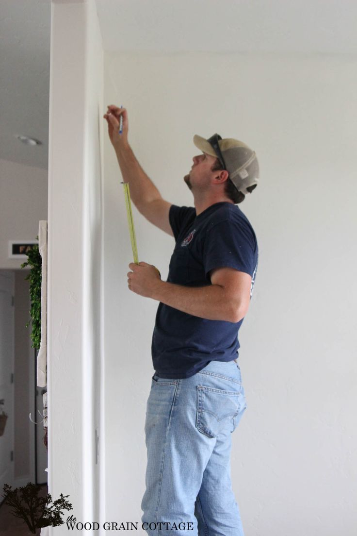 a man is painting the wall with white paint and holding a yellow stick in his hand