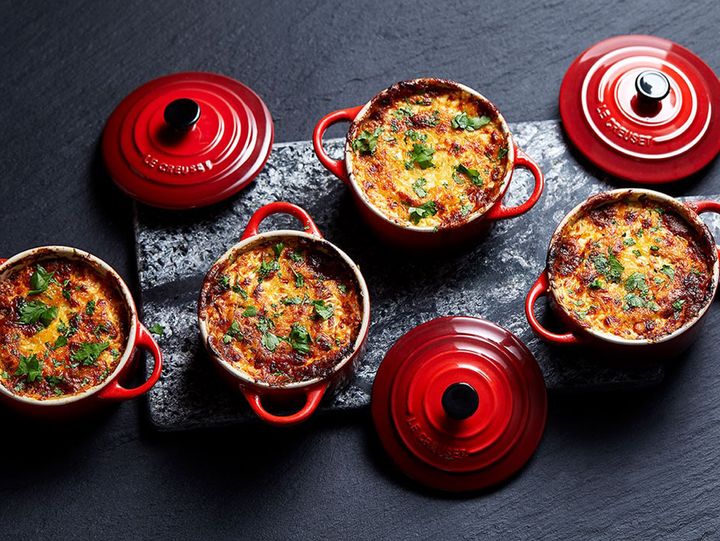 four red pots filled with food sitting on top of a black table next to each other