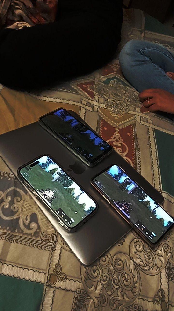 three cell phones sitting on top of a bed next to each other in different positions