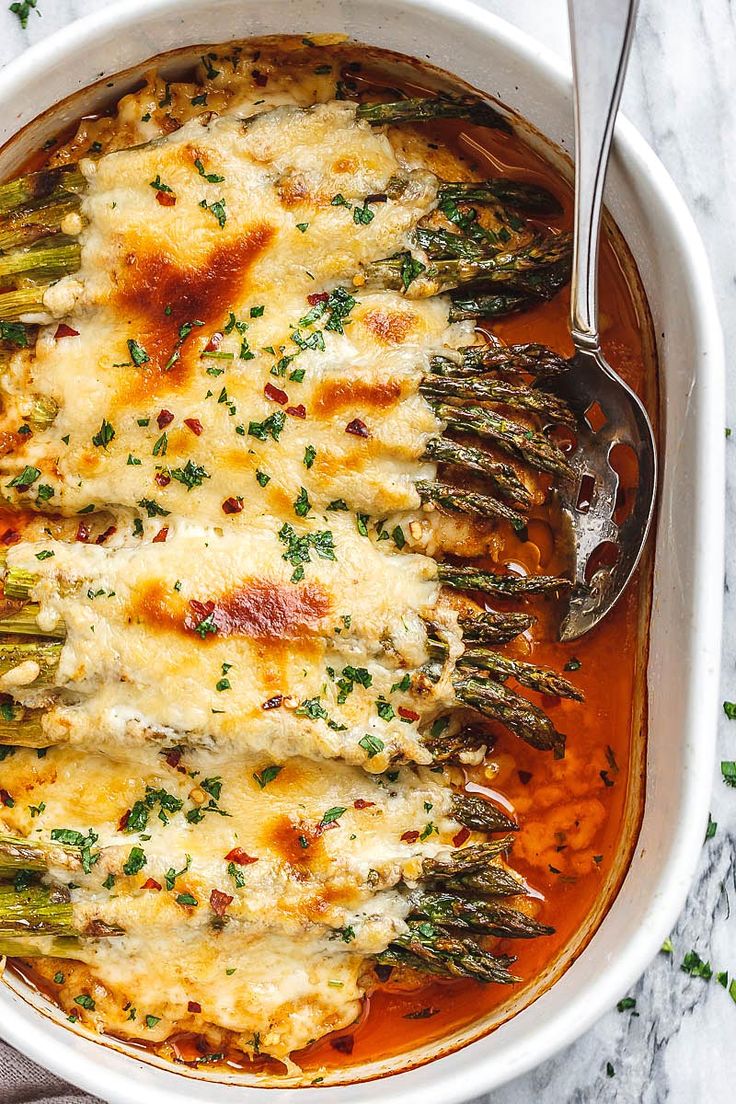 a casserole dish with asparagus and cheese in it on a marble surface