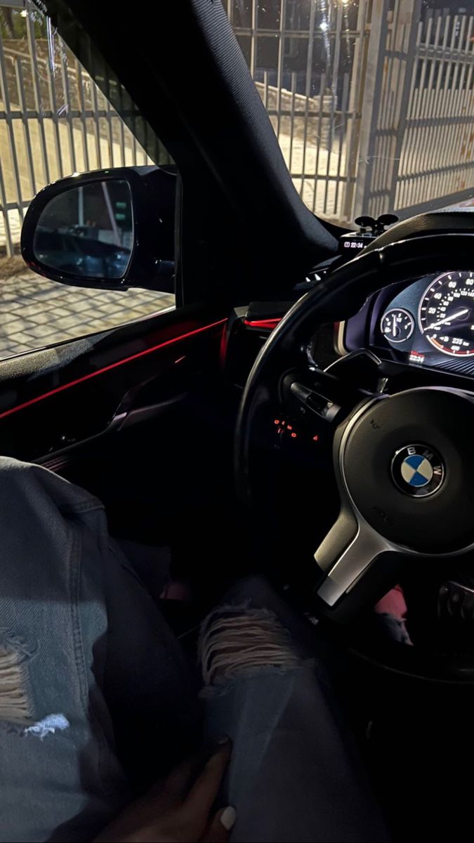 the interior of a car with dashboard, steering wheel and dash lights on display in front of a gated area