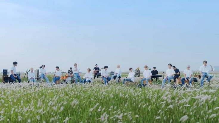 a group of people sitting on top of a lush green field next to tall grass