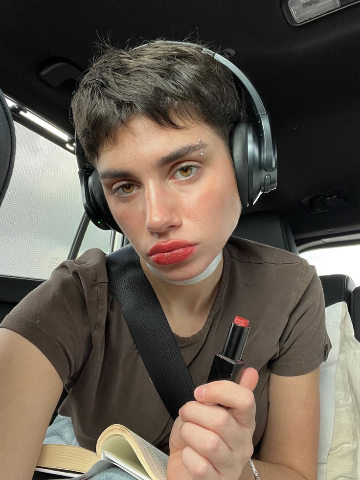 a woman with headphones on sitting in the back seat of a car and holding a book