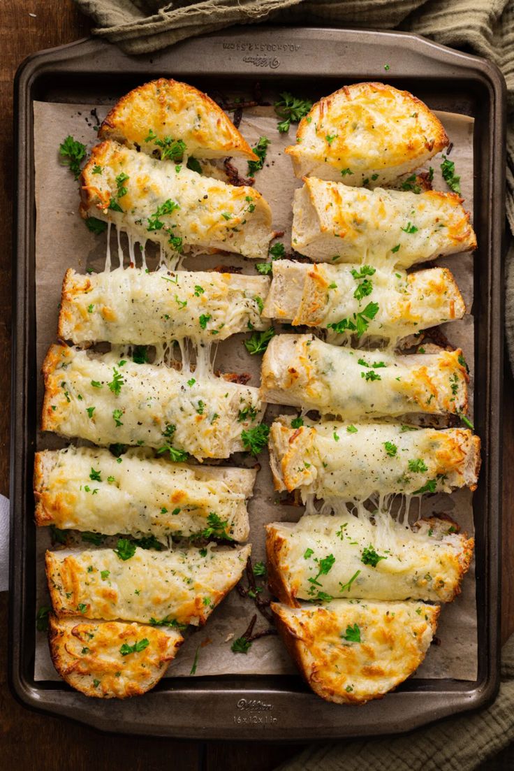 chicken parmesan bread on a baking sheet with melted cheese and parsley sprinkled