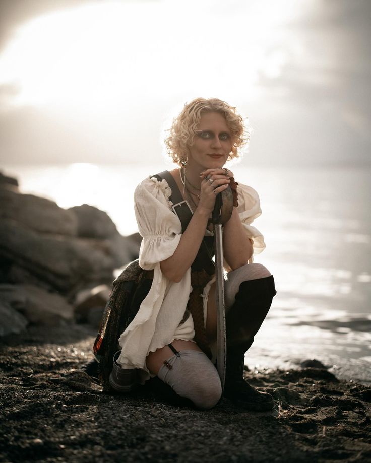 a woman sitting on the beach with her legs crossed