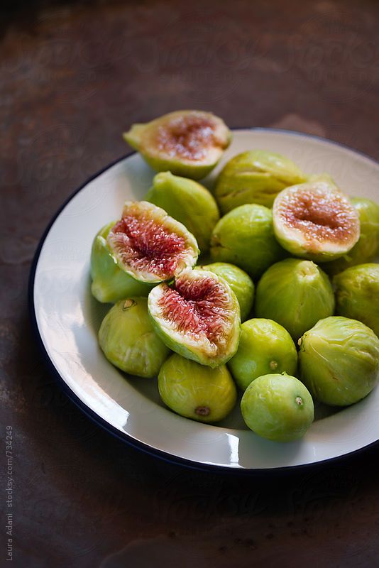 a white plate topped with green figs on top of a table