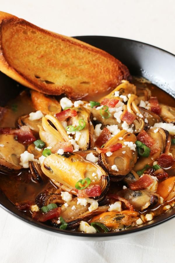 a bowl filled with clams and bread on top of a table