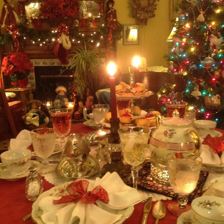 a dining room table set for christmas dinner with lit candles and dishes on the table