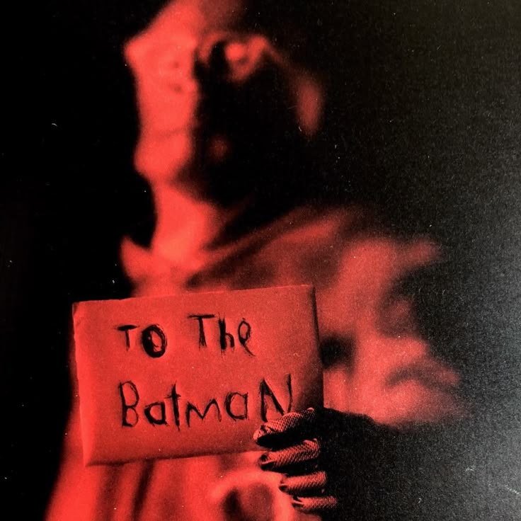 a woman holding a sign that says to the batman